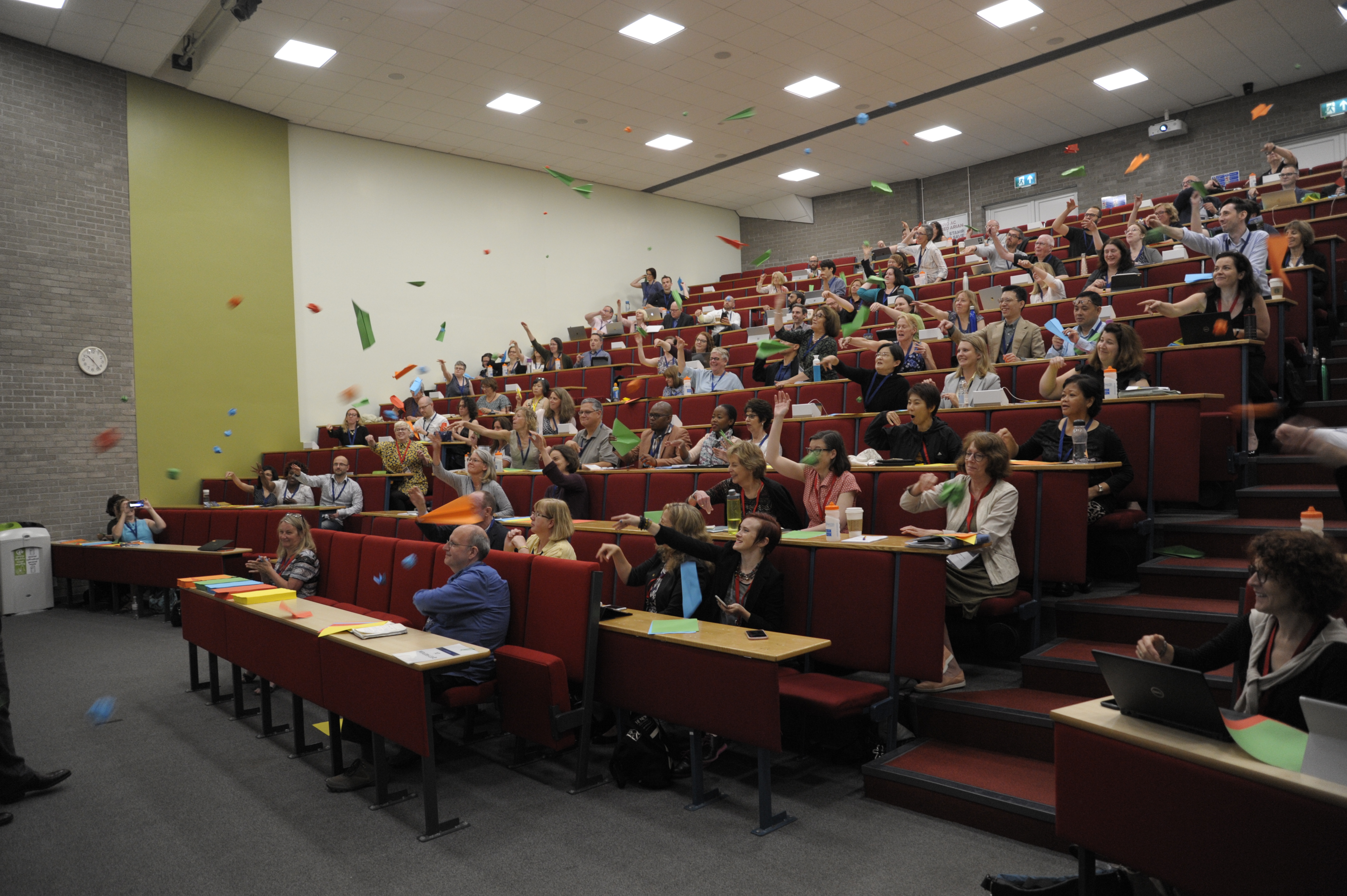 Conference audience throwing paper planes.